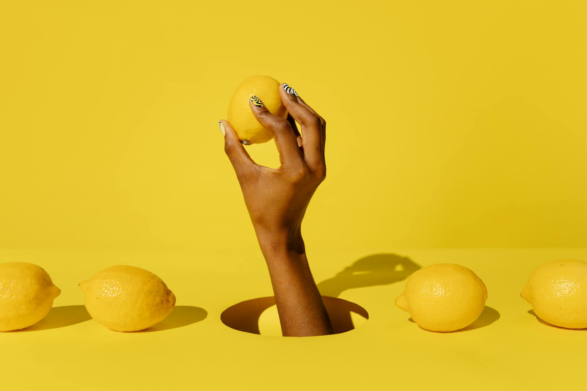 A hand holding a bright lemon against a vivid yellow background, symbolizing fresh and gentle sensations
