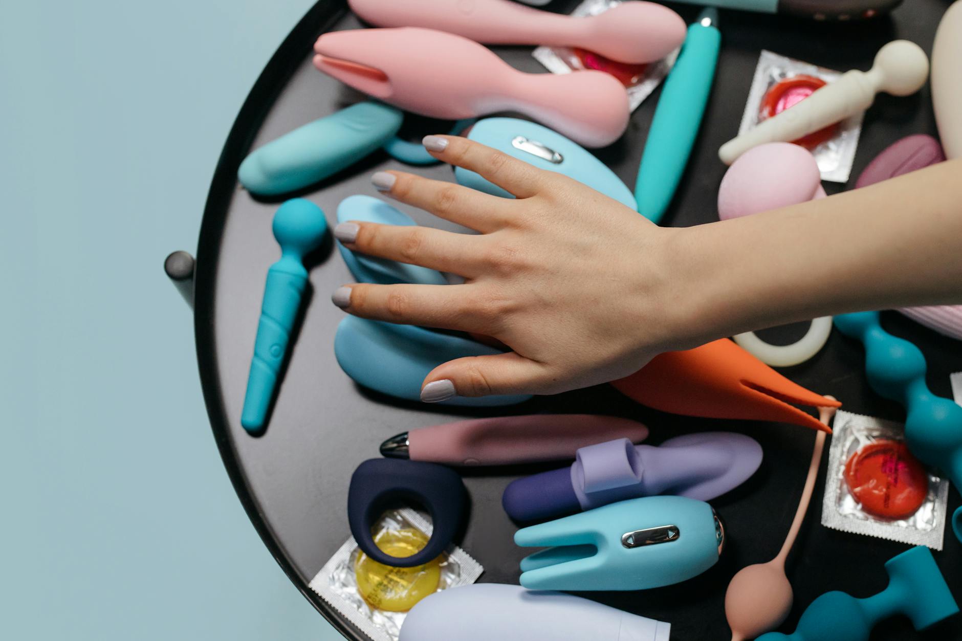 A blue silicone clitoral vibrator held in hand against a solid purple background, representing self-love and personal pleasure exploration.