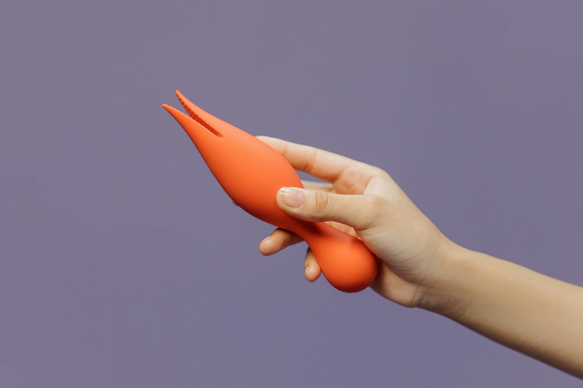 Hand holding a yellow lemon vibrator against a minimalist purple backdrop, representing first-time exploration