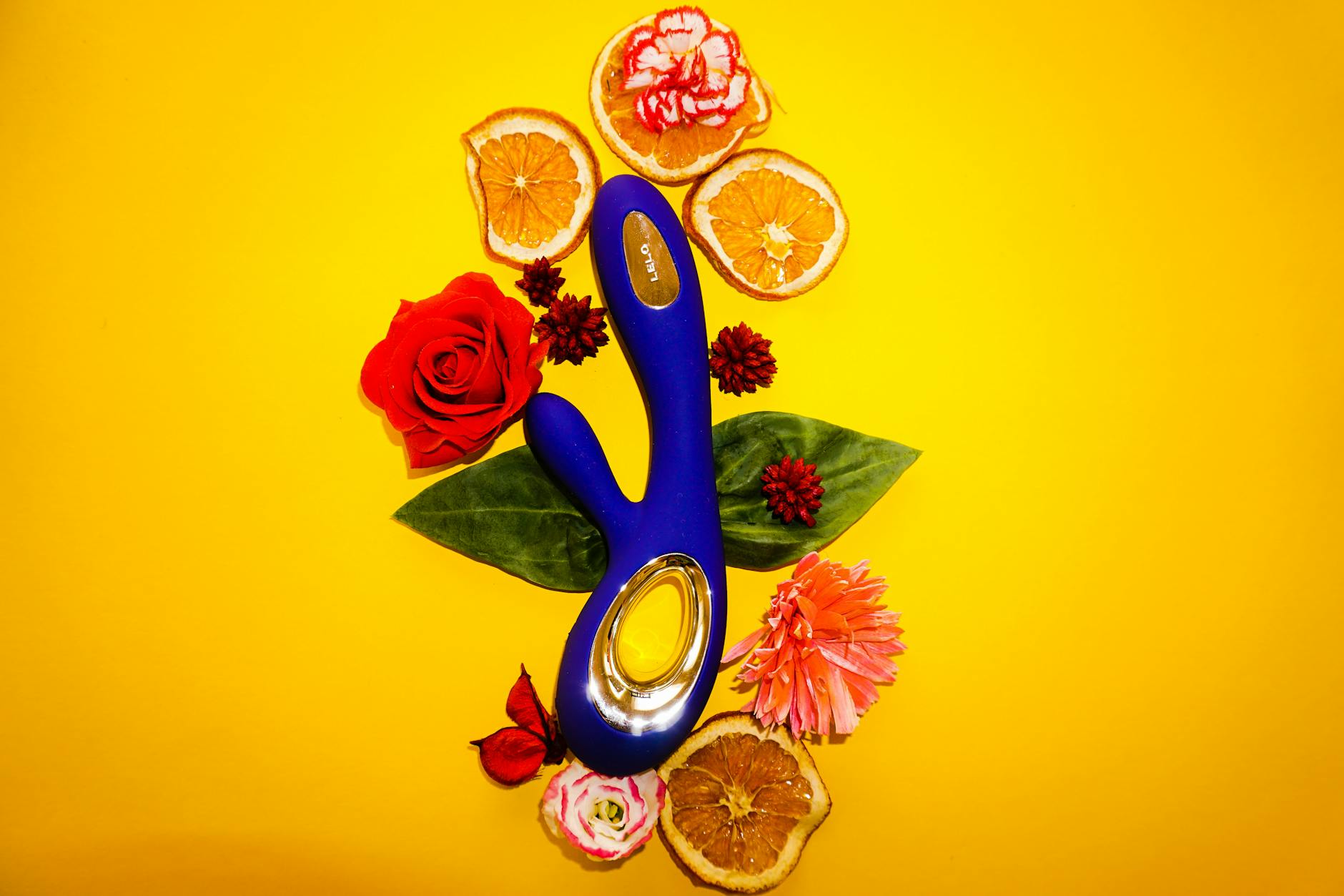 Hand holding a blue clitoral vibrator against a purple background, symbolizing self-care and intimacy